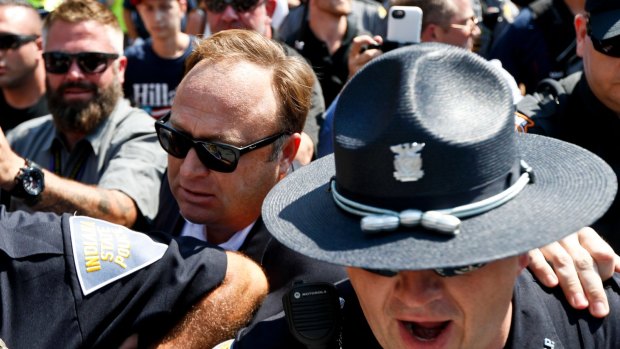 Alex Jones, centre, an American conspiracy theorist and radio show host, is escorted out of a crowd of protesters after he said he was attacked in Cleveland, during the second day of the Republican convention.