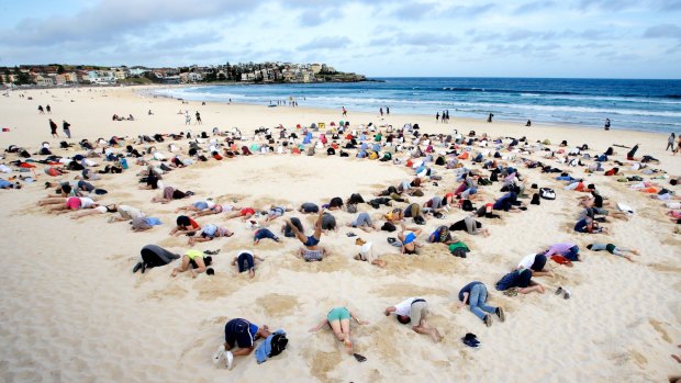 More than 400 people gather at Bondi Beach to bury their heads in the sand to send a climate change message to Prime Minister Tony Abbott during the G20 Summit in 2014.