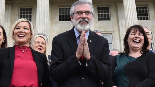 Sinn Fein president Gerry Adams, centre, bows to a group of Japanese tourists as he attends a press call alongside northern leader Michelle O'Neill, left, and Michelle Gildernew at Stormont.