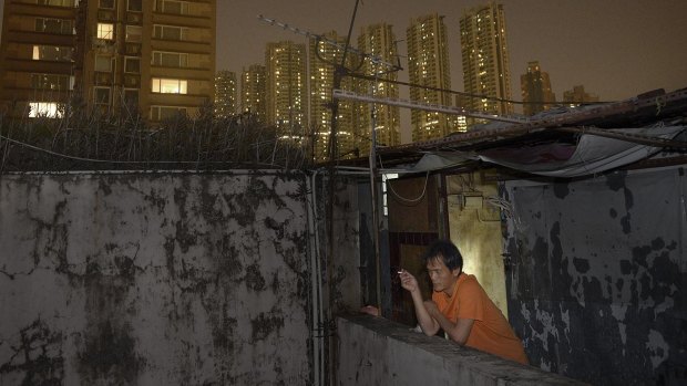 Construction worker Wong Man-chung smoking in front of his rooftop home.