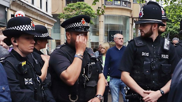 A police officer wipes away tears as he looks at flowers and tributes left in St Ann's Square in Manchester, England.