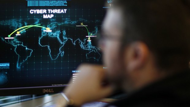 An information analyst works in front of a map tracking cyber threats.
