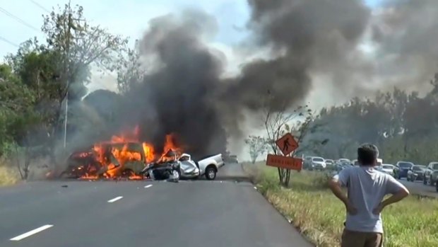 A man watches as two vehicles burn after they collided on a highway east of Bangkok.