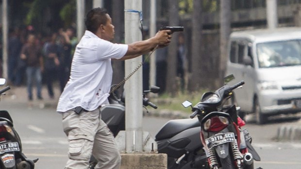 A plain-clothes police officer aims his gun at attackers during a gun battle following explosions in Jakarta.