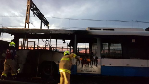 Firefighters sweep water away from a bus blackened by a fire on the Sydney Harbour Bridge.