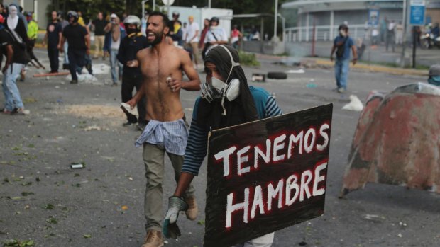A demonstrator holds a sign the reads in Spanish "We are hungry" during clashes with the Bolivarian National Guard in Caracas, Venezuela.