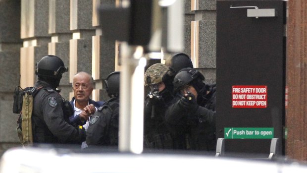 A hostage runs from the Lindt cafe on Monday afternoon. Experts say the siege was most likely the work of a 'lone wolf'