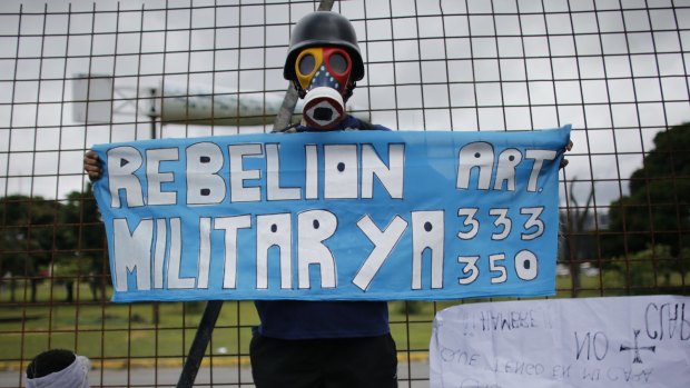 A demonstrator holds a sign calling for a "military rebellion" and citing articles 333 and 350 of the constitution at La Carlota Air Base in Caracas.