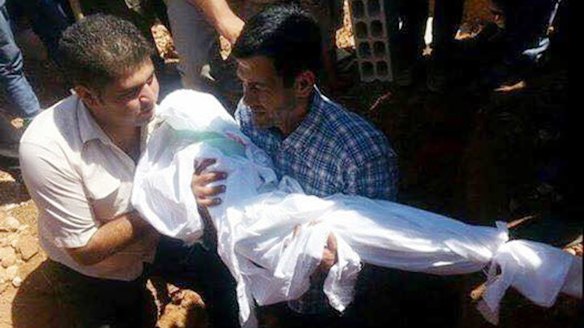 Abdullah Kurdi carries the body of one of his sons during their funeral in Kobane, Syria, last year.