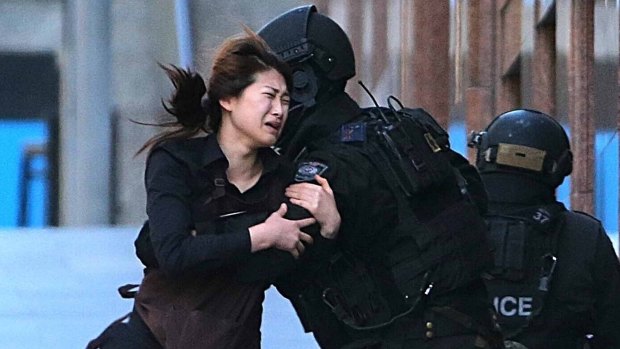 A hostage runs to armed tactical response police officers for safety after she escaped from a cafe under siege at Martin Place.