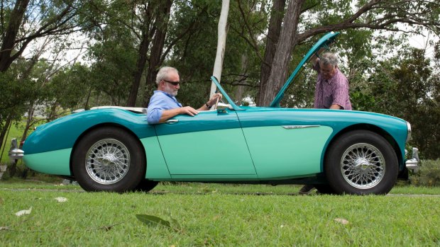 Frank Robson ponders the suspension of the Austin-Healey roadster while owner Paul Blake tinkers under the hood.