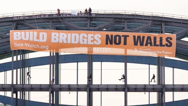Activsts of the refugee support group SeaWatch attach a poster 'Build bridges not walls' to a bridge over the river Elbe in Hamburg.
