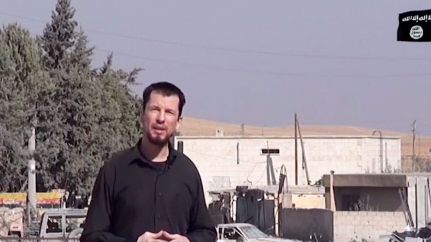 An image grab taken from a video released by IS in October 2014 purportedly shows 43-year-old kidnapped British reporter John Cantlie standing in a war-damaged town, talking to the camera and rejecting US claims that the "mujahideen" are in retreat.