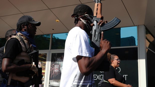 Men, angry with the verdict, hold rifles as they join the protest.