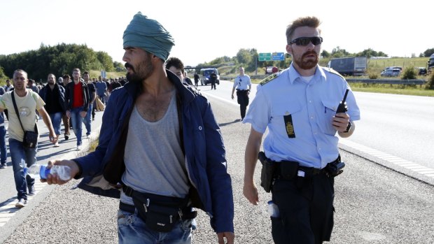 Not in my backyard: Migrants walk north on a highway in southern Denmark. Danish police in September closed a motorway and rail links with Germany as migrants headed north to Sweden.