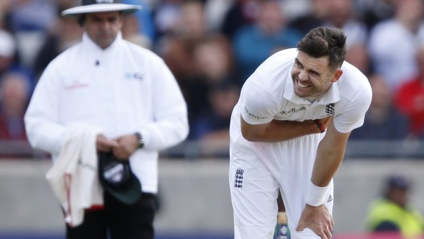 Umpire Aleem Dar looks on as England fast-bowler Jimmy Anderson grimaces due to injury.