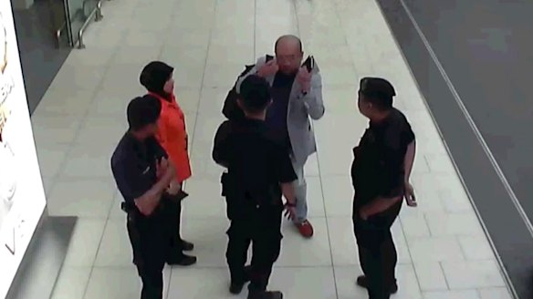 Kim Jong-nam, in grey, gestures towards his face while talking to airport security shortly before his death.