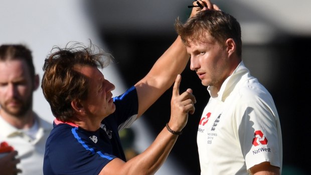Joe Root is checked out by medical staff after being hit in the head.