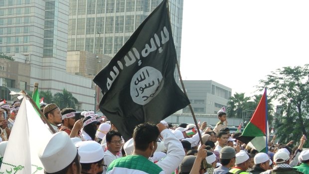A member of the Islamic Defenders Front, an Indonesian radical group, flies the flag used by Islamic State and al-Qaeda at a rally in Jakarta in July 2014.