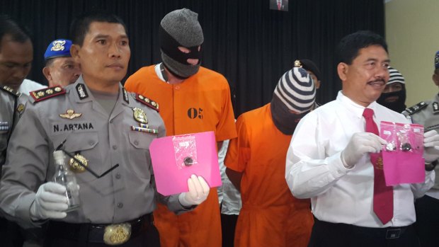 Police with Australian Giuseppe Serafino (in orange prison clothes, right) and Briton David Fox, after their arrest in October last year.