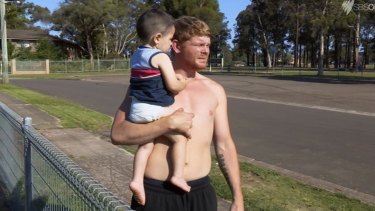 Corey holds his two-year-old son in season one of <i>Struggle Street</i>.