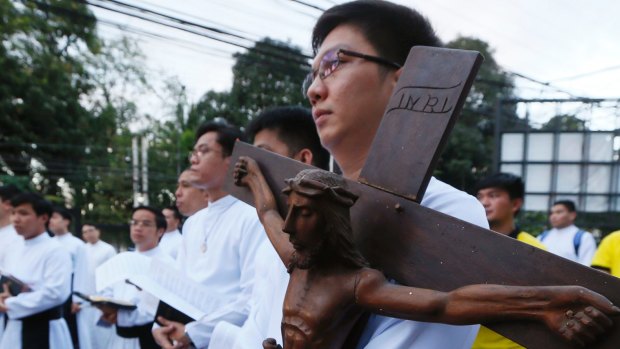 A Catholic priest carries a wooden crucifix during a prayer vigil held last month to protest against the killings in the Philippines as President Duterte pursues his war on drugs. 