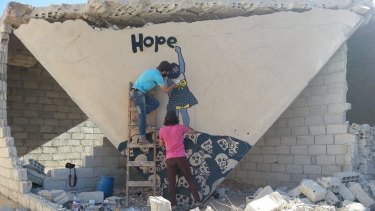 Graffiti artists at work in the ruins of the besieged Syrian city of Daraya.