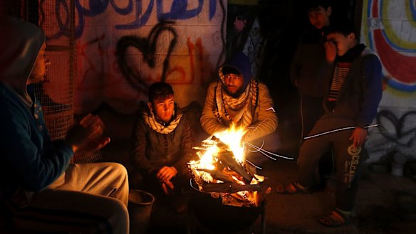 Palestinians, who get only several hours of electricity a day, sit around a fire outside their home in Gaza City. 