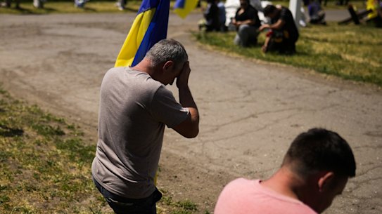 Mourners kneel as they await the coffin of Volodymyr Losev, 38, to pass by during his funeral in Zorya Truda, Odesa region, Ukraine, Monday, May 16, 2022. Volodymyr Losev, a Ukrainian volunteer soldier, was killed May 7 when the military vehicle he was driving ran over a mine in eastern Ukraine. (AP Photo/Francisco Seco)