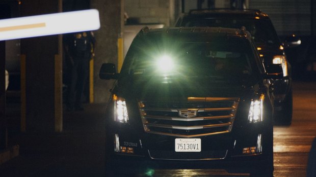 Quick getaway ... A man shines a flashlight to block the view of cameras as two SUVs believed to be transporting Jimmy Page and Robert Plant, two of Led Zeppelin's founder members, depart federal court in Los Angeles.