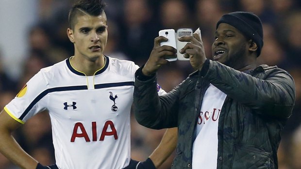 A spectator runs onto the pitch and takes a 'selfie' of himself and Tottenham Hotspur's Erik Lamela.