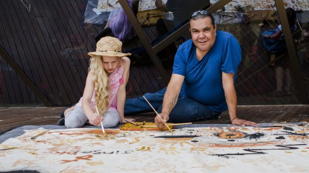 Adrian Brown, a Ngunnawal Country Ranger in the ACT Parks and Conservation Service, helps Paige von Berger, of Ainslie, with the floor mural at the National Museum's Australia Day festival.