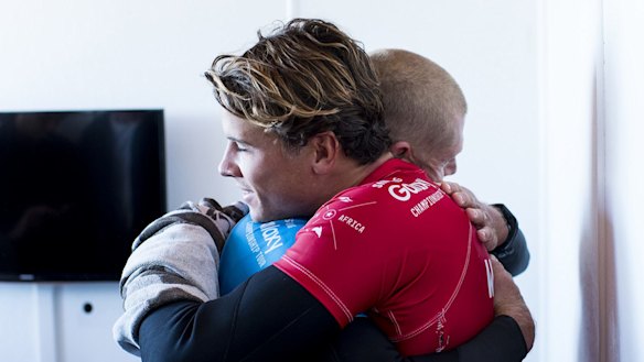 Julian Wilson (in red) hugs Mick Fanning, who was attacked by a shark during the fInal of the J-Bay Open on Sunday.
