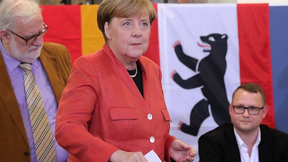 Angela Merkel, Germany's chancellor and Christian Democratic Union (CDU) leader, places her voting slip in a ballot box at a polling station during the federal election in Berlin.