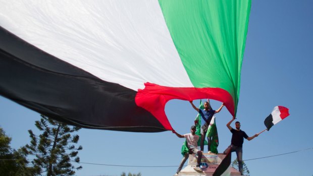 Palestinians wave national and Egyptian flags to celebrate the reconciliation agreement.