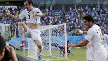Uruguay's Diego Godin jumps over a barricade after scoring his side's winning goal.