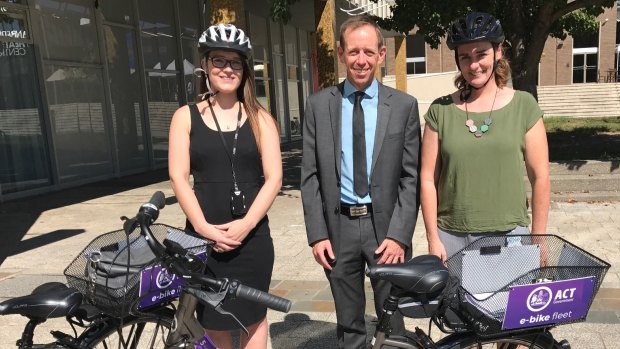 ACT Greens MLA Shane Rattenbury (centre) stands with two staff and one of the government's eight electric bikes.