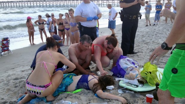 A crowd gathers to assist the teenage girl after she was attacked by a shark in the seaside town of Oak Island. 