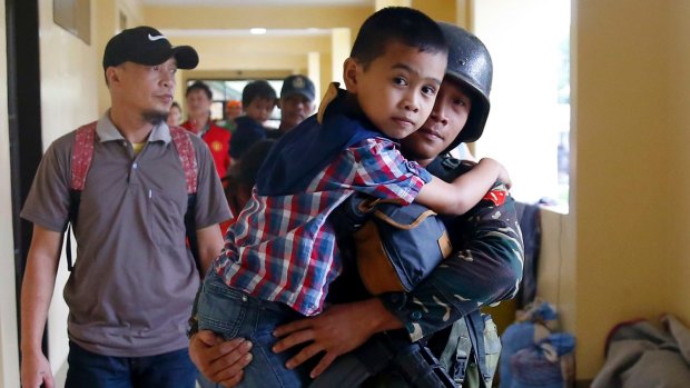 A government solider carries a boy to a processing center after being rescued from the site of the fighting between the Philippine troops and Muslim militants in Marawi city on Wednesday.