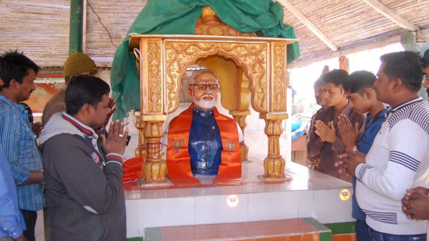 Indian villagers assemble and pray by an idol of Indian Prime Minister Narendra Modi.
