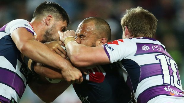Getting a grip: Storm defenders put the brakes on Rooster Sam Moa.