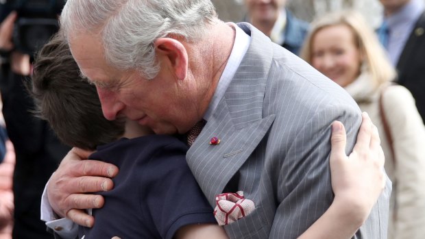 Prince Charles receives a hug from Valentin Blacker, son of William Blacker who is a local conservationist, during a walking tour of the Old Town in Bucharest.