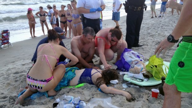 A crowd gathers to assist the teenage girl after she was attacked by a shark in the seaside town of Oak Island. 