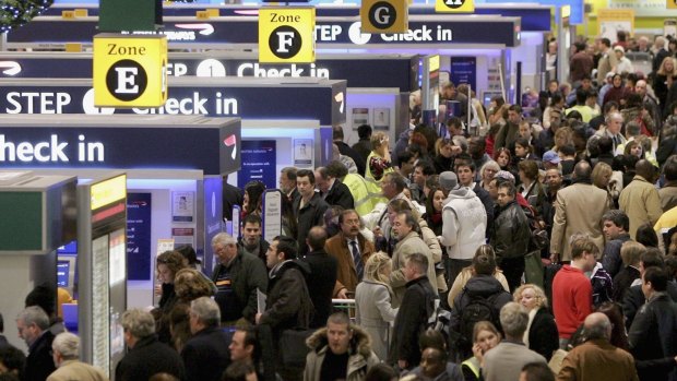 Passengers queue to check-in at Heathrow Airport in London.
