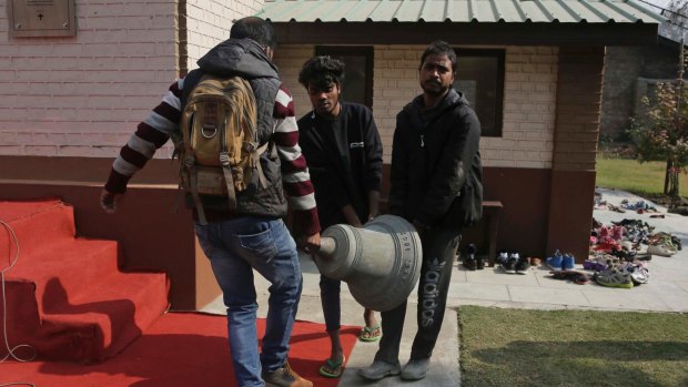 People carry an old bell that was damaged in an incident of arson in 1967 after removing it at the Holy Family Catholic Church in Srinagar, Indian controlled Kashmir.