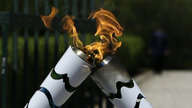 Still alight: The Olympic flame is still burning despite a man throwing a bucket of cold water over it. 