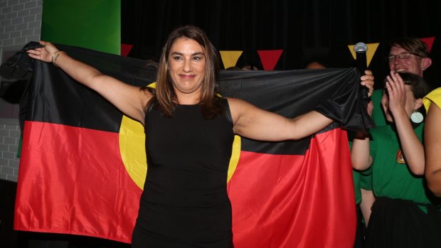 New Indigenous MP Lidia Thorpe, draped in the Aboriginal flag, celebrates her win in Northcote.