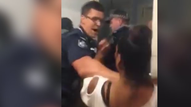 Police argue with a woman as they arrest a man at Zillmere.