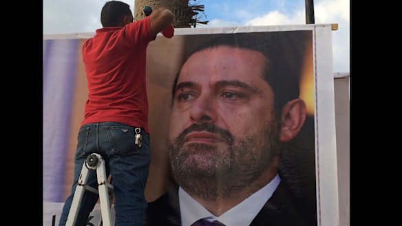Workers hang a poster of former PM Saad Hariri in Beirut saying: "We are all Saad".