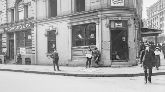 Hunter and O'Connell streets, 1919
Photographer: Milton Kent.

When this corner building was captured by the camera on 19 February 1919, Sydney was in the midst of an outbreak of the deadly âSpanishâ influenza pandemic. The requirement to wear a mask in public was enforced by police. Not all obeyed this command. The two young men outside Horwood &amp; Co have slipped their masks off. The windows of Lubrano &amp; Ferrari are marked with crosses.

City of Sydney Archives A-01000471